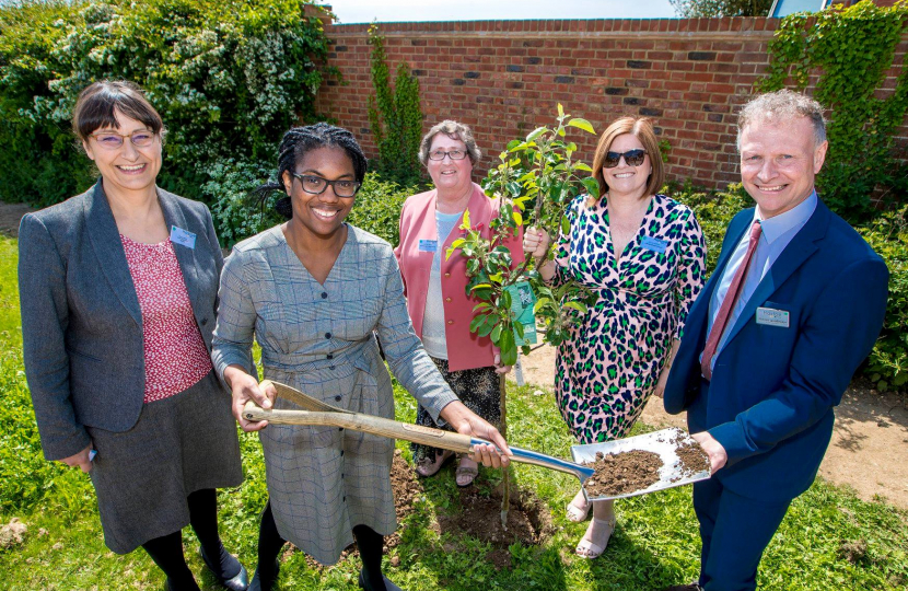 Kemi plants a tree. All smiles.